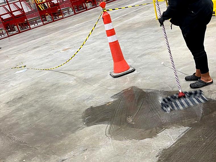Limpeza de piso em galpão com sinalização de área molhada